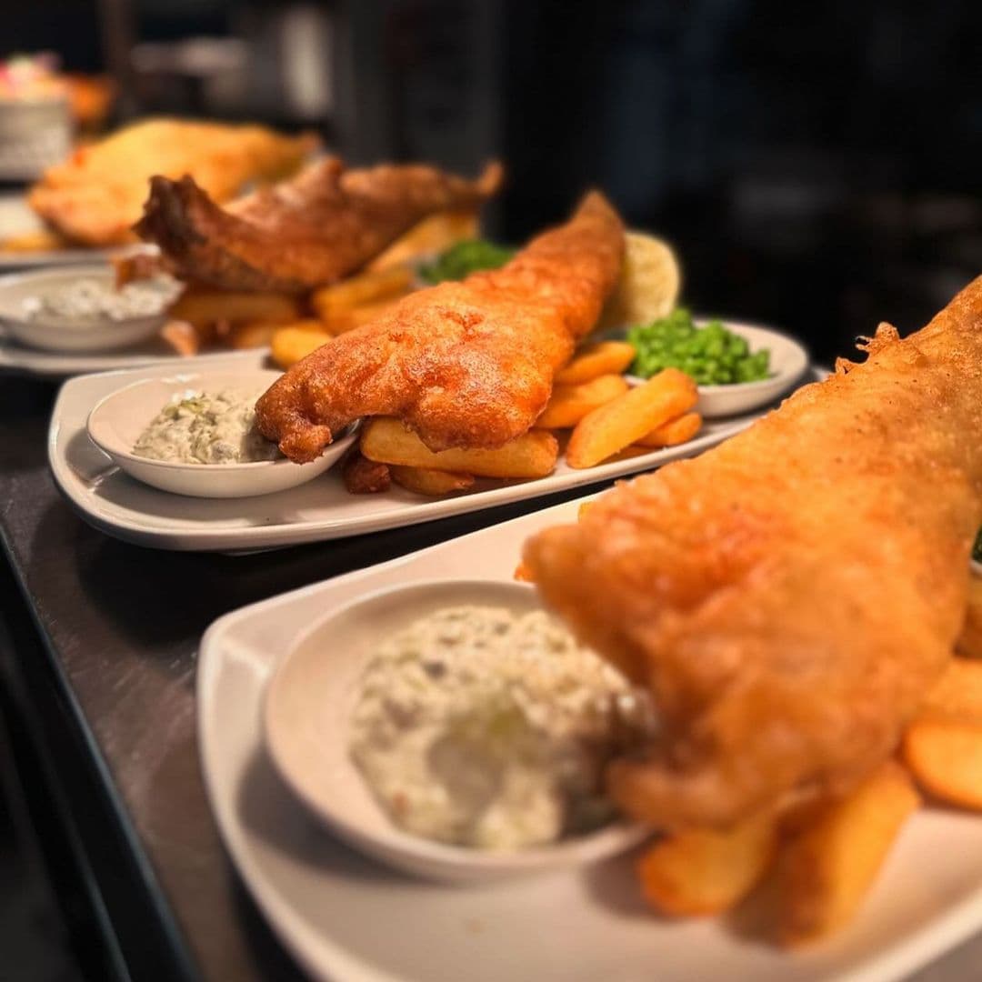 Deer Park Hotel fish and chips gourmet dining delicious Delicious fish and chips served at Deer Park Hotel, featuring golden-battered fish, crispy fries, and a side of tartar sauce. Fresh green peas add a pop of color to the plate.
