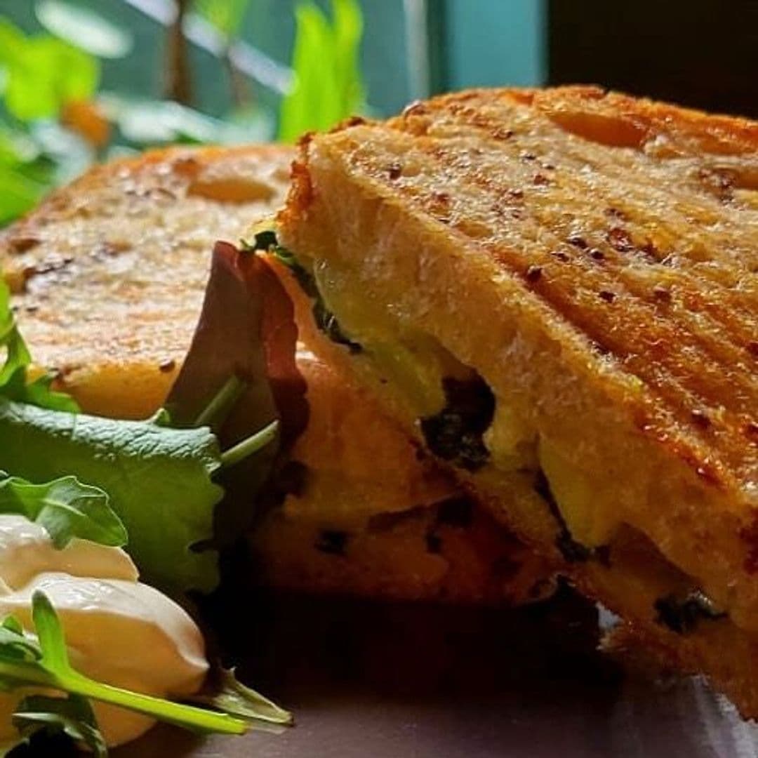 Holding Patterns gourmet sandwich fresh salad delicious meal Delicious grilled sandwich with melted cheese and greens, served with a side of fresh salad and creamy dressing at Holding Patterns.