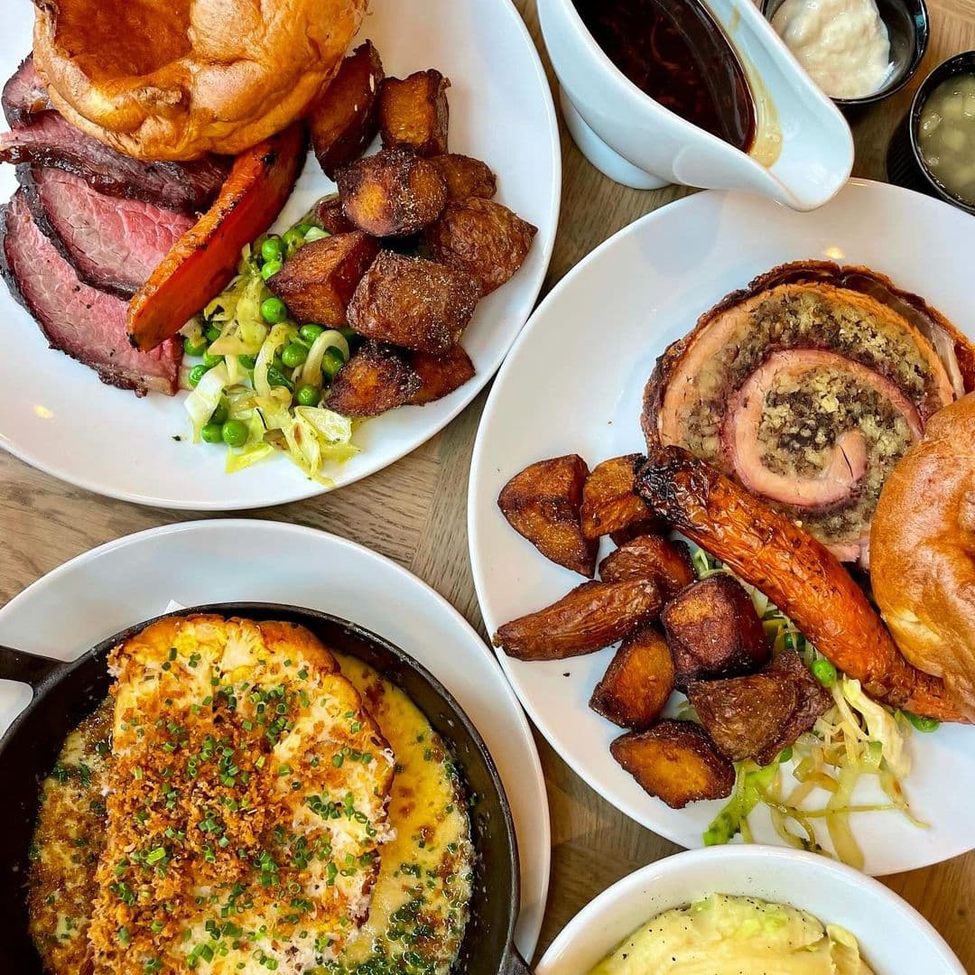 Woodside Neighbourhood Bar Eatery delicious dishes gourmet foods dining experience Delicious dishes served at Woodside Neighbourhood Bar & Eatery, featuring roast beef, crispy potatoes, and a savory baked dish topped with herbs. The meal is beautifully presented on white plates, showcasing a variety of flavors and textures.