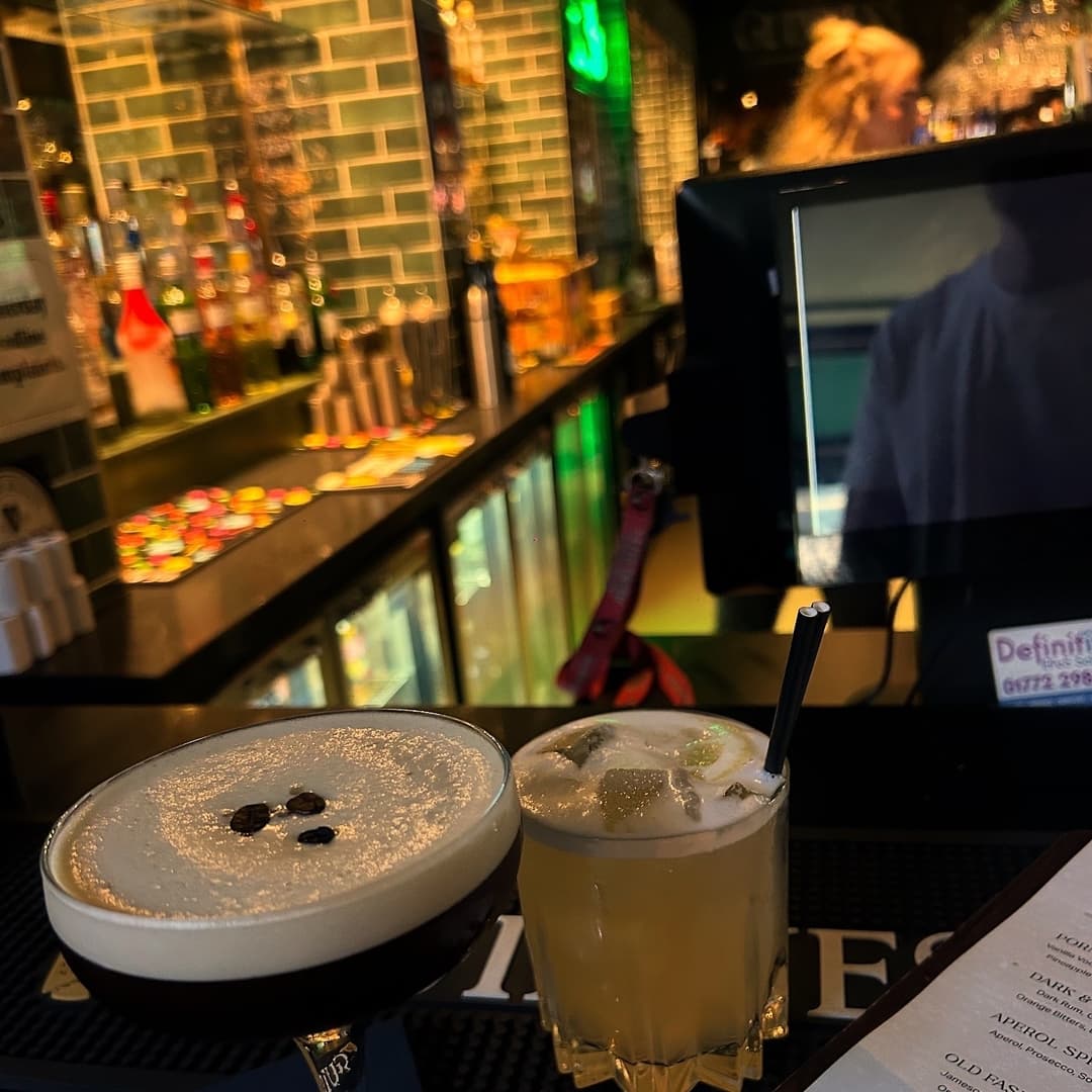 Artfully Crafted Cocktails at the Bar Two cocktails on a bar top: a creamy espresso martini with coffee beans and a refreshing citrus drink with ice.