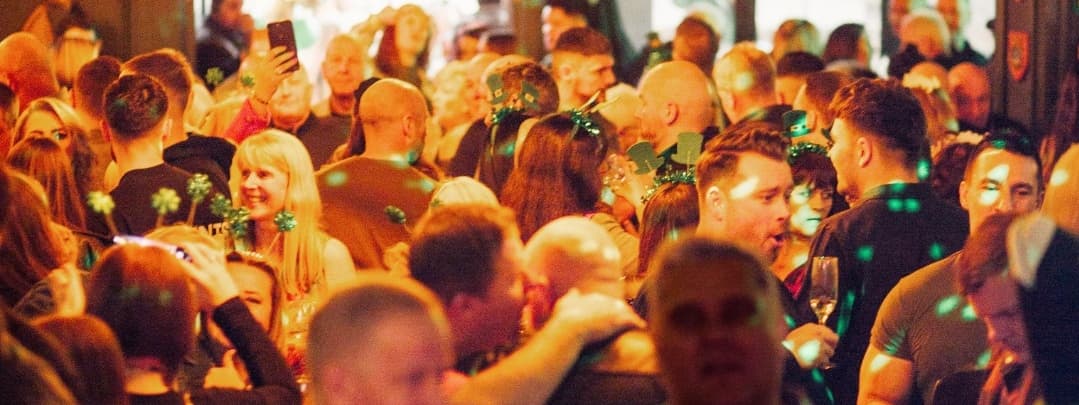 Lively crowd celebrating at Katie O'Brien's Irish Tavern, adorned with festive decorations and green accessories.