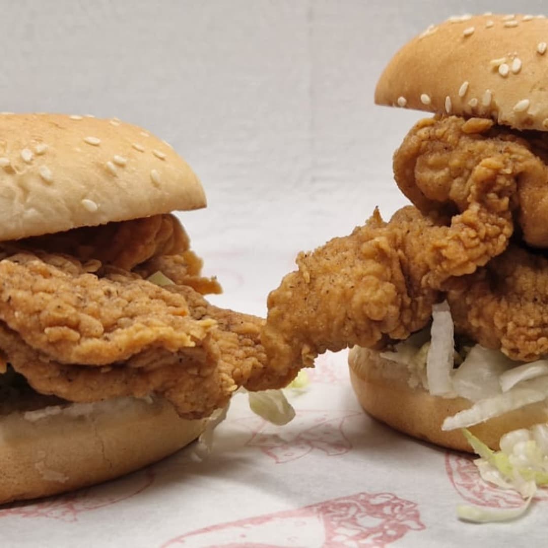 Fatbros — fried chicken burgers Two halal fried chicken burgers in sesame buns at Fatbros, Bramley, Leeds, served on branded tissue paper.